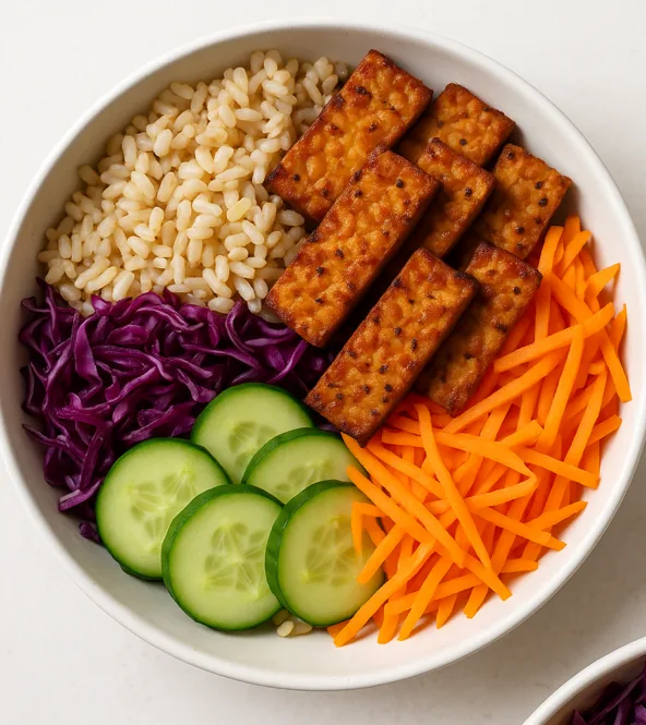 Bol de riz complet, tempeh mariné et crudités colorées